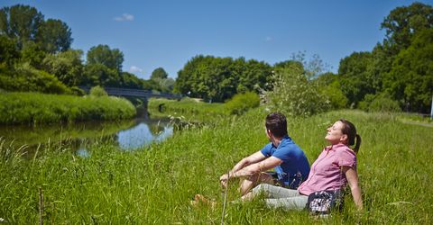 Zwei Personen sitzen am Ufer der Vechte auf dem Rasen